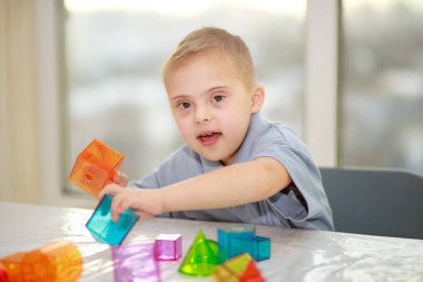 Down sendromlu bir çocuk geometrik figürlerle oynar, plastik bir yapıcı, tip 21 trisonomi, ekstra bir kromozom..