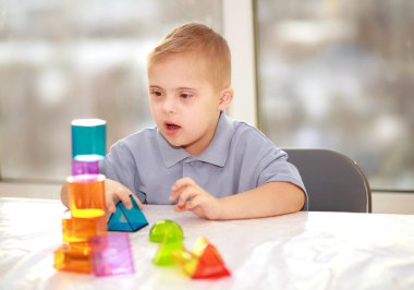Down sendromlu bir çocuk geometrik figürlerle oynar, plastik bir yapıcı, tip 21 trisonomi, ekstra bir kromozom..