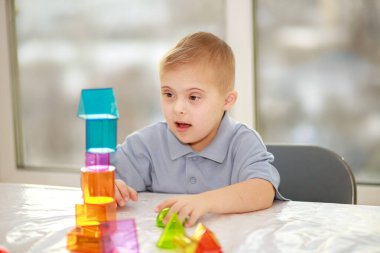 Down sendromlu bir çocuk geometrik figürlerle oynar, plastik bir yapıcı, tip 21 trisonomi, ekstra bir kromozom..