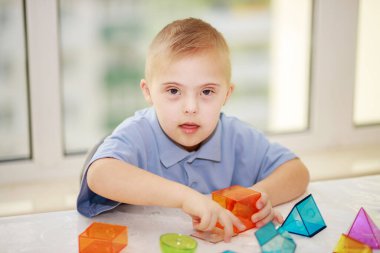 Down sendromlu bir çocuk geometrik figürlerle oynar, plastik bir yapıcı, tip 21 trisonomi, ekstra bir kromozom..