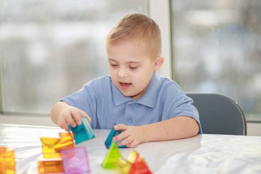 Down sendromlu bir çocuk geometrik figürlerle oynar, plastik bir yapıcı, tip 21 trisonomi, ekstra bir kromozom..