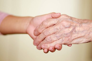 Çocuğun elleri büyükannenin ellerinde, yaşlı kadının yaşlı kahverengi teni, anne sevgisi ve bakımı..