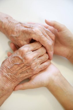 Çocuğun elleri büyükannenin ellerinde, yaşlı kadının yaşlı kahverengi teni, anne sevgisi ve bakımı..