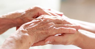 Çocuğun elleri büyükannenin ellerinde, yaşlı kadının yaşlı kahverengi teni, anne sevgisi ve bakımı..