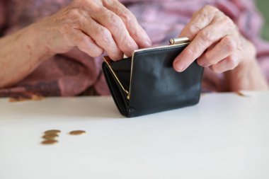Yaşlı bir kadının elinde bir cüzdan. Bir büyükanne, boş deri cüzdanına bozuk para koyar ve sayar. Eski neslin yoksulluğu ve sefaleti..