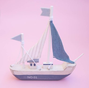 Pembe arka planda yelkenli geminin minyatür modeli