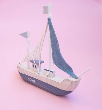 Pembe arka planda yelkenli geminin minyatür modeli
