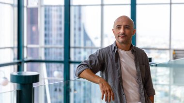 Topuz şeklinde saç stili olan genç SMART CEO 'su, şehir veya şehir merkezindeki gökdelenlerin olduğu terasta bir fincan kahve içiyor. Şehir manzarası olan bir işadamı pencerenin yanında duruyor.