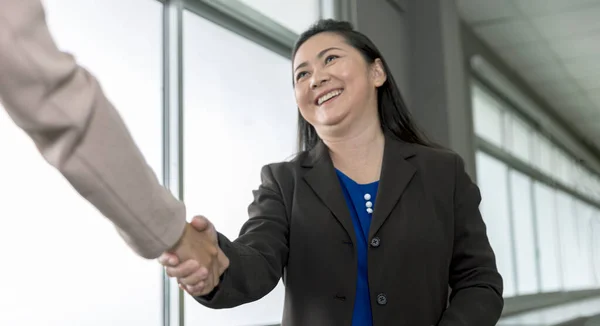 Female business woman with confident shakes hand with another female worker express gratitude and happiness on partnership. Business woman is happy with an agreement while shaking hand with colleague