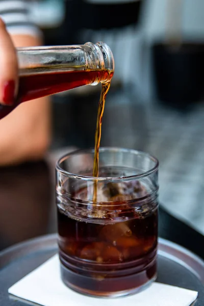 Pouring cold brew iced coffee in glass cup with ice cubes , coffee consept. High quality photo