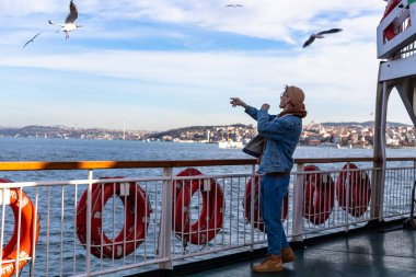 Genç turistler feribotta martılara yemek veriyor, turistik aktiviteler yapıyor. Yüksek kalite fotoğraf