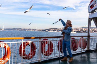 Genç turistler feribotta martılara yemek veriyor, turistik aktiviteler yapıyor. Yüksek kalite fotoğraf