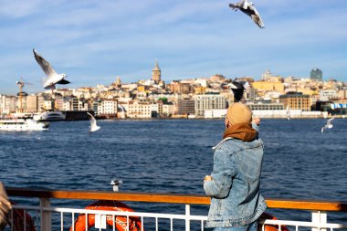 Genç turistler feribotta martılara yemek veriyor, turistik aktiviteler yapıyor. Yüksek kalite fotoğraf