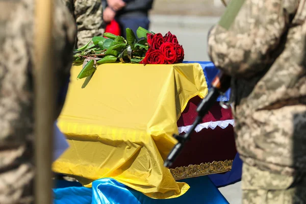 ウクライナのポルタヴァ 2022年3月24日 兵士はウクライナ軍の兵士の埋葬式中にウクライナの国旗で覆われた墓の上に花を保持しています — ストック写真