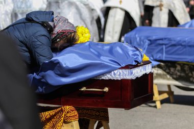 POLTAVA, UKRAINE - 28 Mart 2022 'de mezarın yanındaki meydanda, Ukrayna Silahlı Kuvvetleri' nin Ukrayna-Rusya savaşı sırasında ölen askeri oğlunun yasını tutan bir kadın