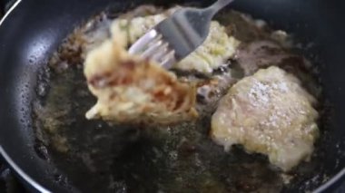 Şef bir restoranda teflon kaplı bir tavada tavuk parçaları kızartıyor.