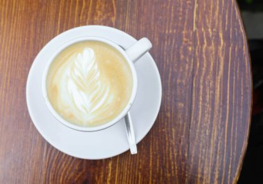 Gün boyunca tahta kahverengi bir masanın üzerinde bir fincan kahve var.