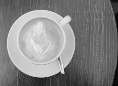 Gün boyunca tahta kahverengi bir masanın üzerinde bir fincan kahve var.