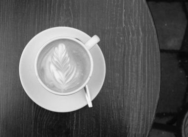 Gün boyunca tahta kahverengi bir masanın üzerinde bir fincan kahve var.