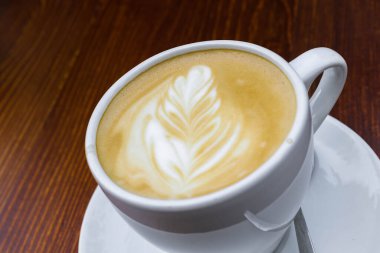 Gün boyunca tahta kahverengi bir masanın üzerinde bir fincan kahve var.