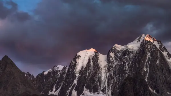 Тёмный Горный Ландшафт Огромной Снежной Горой Освещенной Рассветом Солнца Среди — стоковое фото