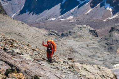 Dağlarda büyük sırt çantalı sakallı genç turist elleriyle el sallıyor.. 