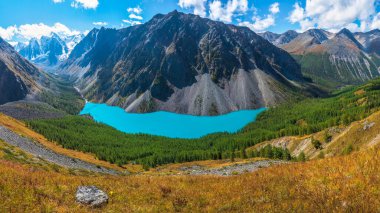 Caldera 'daki Mavi Dağ Gölü. Mavi bulutlu gökyüzüne karşı sıradağlar. Sönmüş bir volkanın Caldera 'sı bir dağ silsilesiyle çevrilidir. Vadide sarp kayalıkları olan mavi bir göl var.