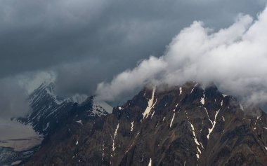 Buzullu dramatik bir manzara. Atmosferik minimalizm, büyük kar dağlarının tepeleri, dramatik gökyüzünde karanlık buzullar..