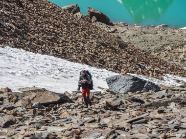 Dik, karlı bir yamaçta ağır tırmanış. Dağlarda tek başına yürüyüş. Seyahat fotoğrafçısı yaşam tarzı, yürüyüş, bahar tatilinde macera konsepti..