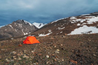 Güneşin doğuşunda kayalıkların arasında kayalık tepede çadırlı dağlık bir arazi. Dağlık bölgelerde, bulutlu havalarda çadırlı gerçeküstü bir manzara.. 