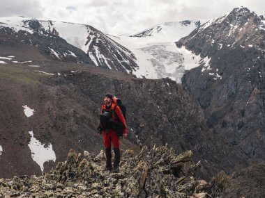 Profesyonel fotoğrafçı bir dağın tepesinde durur ve manzaraya bakar. Üst dağların muhteşem manzarası. Aktif dinlenme, dağlara yolculuk..