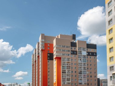Modern inşaat, yeni mahalle. Güzel yeni binalar. Mavi bulutlu gökyüzünün arka planında renkli bir duvar. Boşluğu kopyala.
