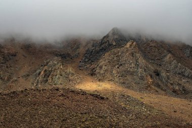 Korku dağı gölgeleri. Dev kayalık dağların arasında dramatik bir sis. Büyük kayalıklara hayali atmosfer manzarası. Alçak bulutlar ve güzel kayalar. Minimalist manzara gizemli bir yer..