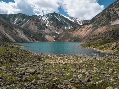 Caldera 'daki Mavi Dağ Gölü. Bulutlu bir gökyüzüne karşı sıradağlar. Sönmüş bir volkanın Caldera 'sı bir dağ sırası ile çevrilidir. Yaz mevsiminde yüksek irtifada kamp kurarlar.. 