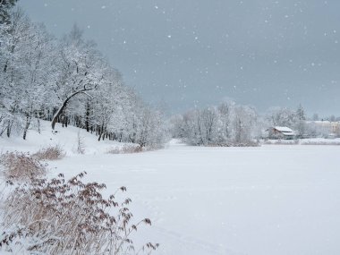 Minimalistic winter background with a village on the shore of a snow cover by the lake. Lots of snow winter countryside landscape.
