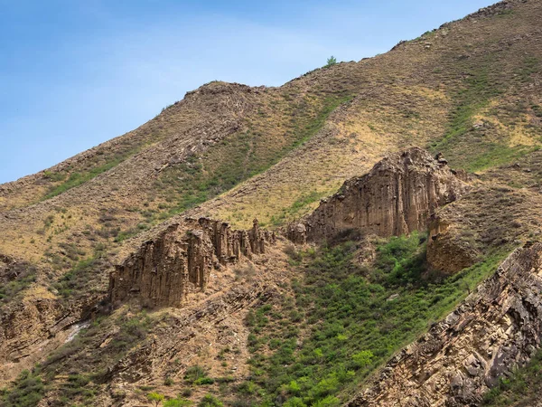 Gevşek kaya. Güneşli ışıkta sivri tepeli kayalık dağ duvarlı atmosferik manzara. Ön planda gevşek taş dağ yamacı. Keskin taşlı dağlar.
