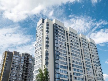 Modern inşaat, yeni mahalle. Güzel yeni binalar. Mavi bulutlu gökyüzünün arka planında renkli bir duvar. Boşluğu kopyala.