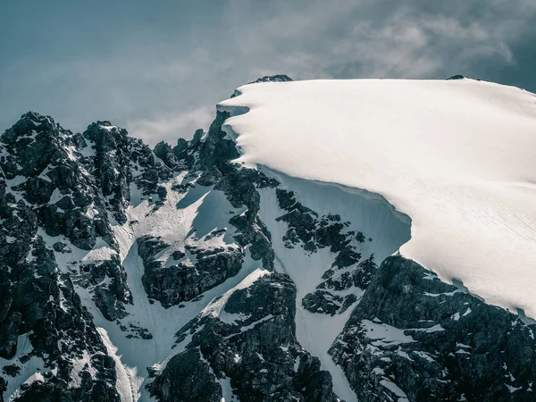 明亮的高山风景 白雪覆盖的山顶 阳光下的黑色岩石 高山简约主义 雪山蓝天 在很高的高度俯瞰雪山峰顶的极小景观 — 图库照片