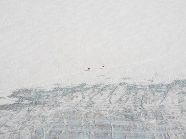 Buzulda iki küçük yürüyüşçüyle minimalist bir manzara. Aşırı eğlence ve dağ turizmi. Takım yürüyüşçüleri dağ yolundan gider.. 