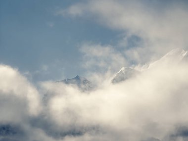 Yumuşak odaklanma. Alçak bulutların üzerinde karlı dağ zirveleri olan harika minimalist manzaralar. Atmosferik minimalizm, bulutlu gökyüzünde büyük kar dağlarının tepeleri..