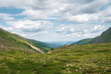 Güneş ışığında yüksek yeşil dağ vadisi olan minimalist alp manzarası. İskoçya 'da değişken hava koşulları olan manzaralı dağ manzarası. Güneş ışığı ve gölge. Alp yeşil eğiminin dokusu.