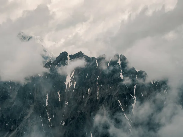 Soft focus. Minimalist mountain landscape. Wonderful minimalist landscape with big snowy mountain peaks above low clouds. Atmospheric minimalism with large snow mountain tops in cloudy sky.