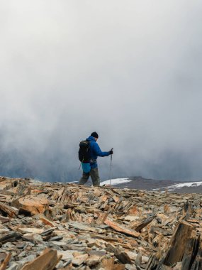 Solo climbing. Activities man climb to the top of a misty stone hill.  People in difficult conditions. Difficult climb to the top of the mountain. Vertical view.
