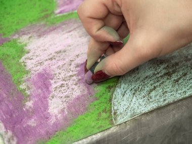 Hand is in motion. Drawing with pastels close-up. Woman drawing beautiful crocus flowers with soft pastel at table. Close up.