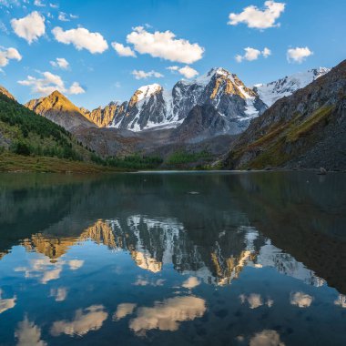Beautiful evening landscape with glacier reflection in water surface of mountain lake. Snowy mountain reflected in clear water of glacial lake. Snow on rock reflected in mountain lake.