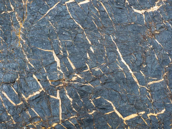 Gold-veined stone, a natural mineral Textured vivid geological background with rude stones. Amazing mineral. Piece of rock.