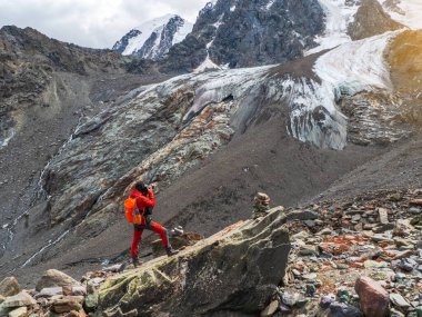 Photographer tourist on the rock. Dangerous mountains and abyss. Stunning view of the mountain valley under the blue glacier.
