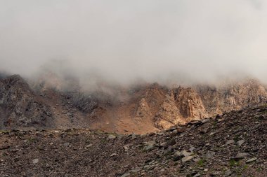 Yumuşak odaklanma. Yoğun bir siste dağlar. Alçak bulutlarda güzel, keskin kayalar olan mistik bir manzara. Güzel dağ sisli manzarası uçurumun kenarında keskin taşlarla.