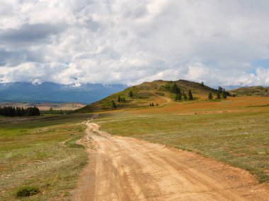 Way to the distance, way over the hill to the sky. Dirt road through the field. Field with a dirt road.