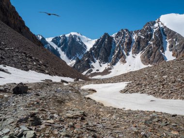 Deep mountain hiking. Atmospheric mountain landscape with great snow-covered pinnacle and snowy pointy peak in blue sky. 
